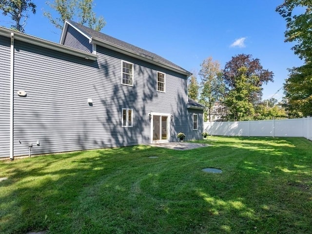 rear view of property featuring a patio, fence, and a lawn