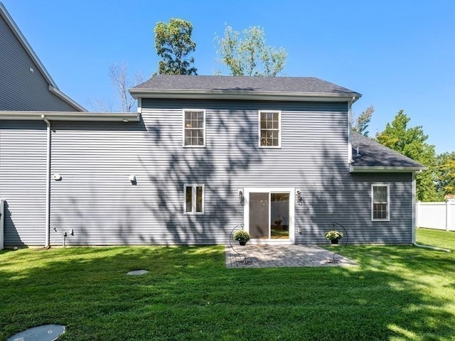 rear view of property with fence, a patio, and a lawn