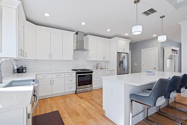 kitchen featuring visible vents, white cabinetry, wall chimney exhaust hood, and stainless steel appliances