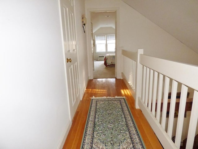 hallway featuring light hardwood / wood-style floors, lofted ceiling, and a wall mounted AC