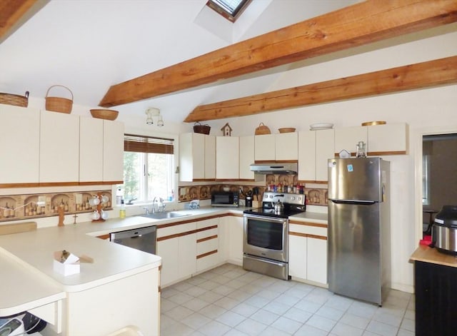 kitchen featuring white cabinets, sink, vaulted ceiling with skylight, light tile patterned floors, and appliances with stainless steel finishes