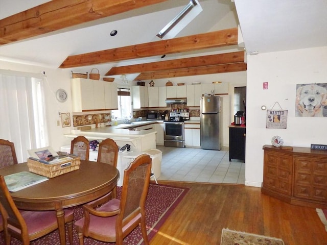 dining space featuring wood-type flooring and vaulted ceiling with beams