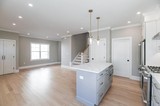 kitchen featuring a center island, appliances with stainless steel finishes, white cabinets, pendant lighting, and light stone counters