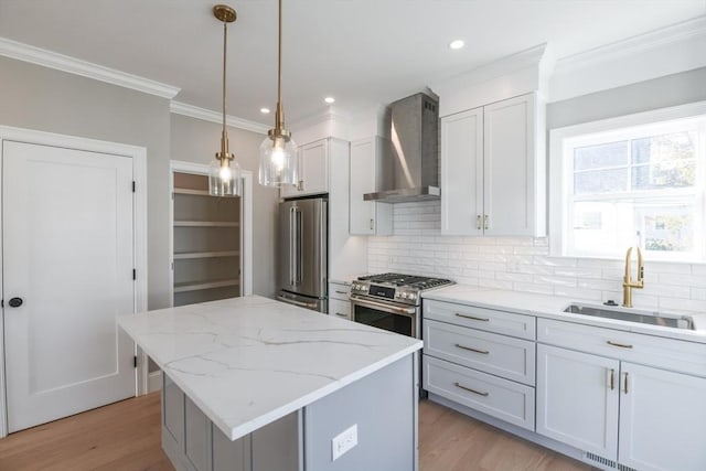 kitchen with a center island, light stone countertops, high end appliances, wall chimney range hood, and sink