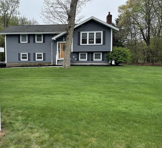 split foyer home featuring a chimney, a front yard, and entry steps