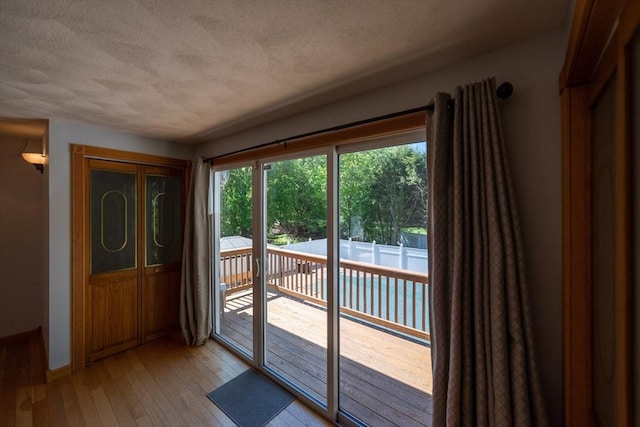 entryway featuring a textured ceiling, light wood-style floors, and baseboards