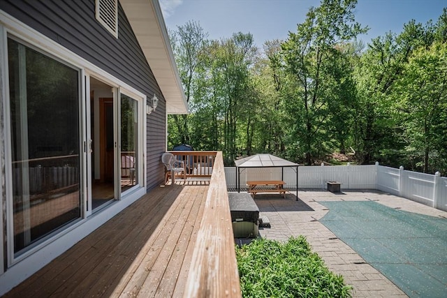 deck featuring a fenced backyard, a patio, and view of wooded area