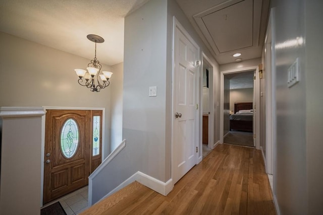 entrance foyer with baseboards, light wood finished floors, and a chandelier