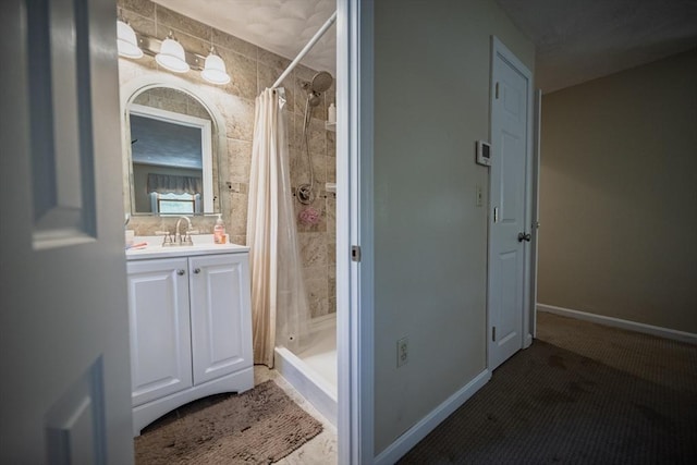bathroom featuring a stall shower, vanity, and baseboards