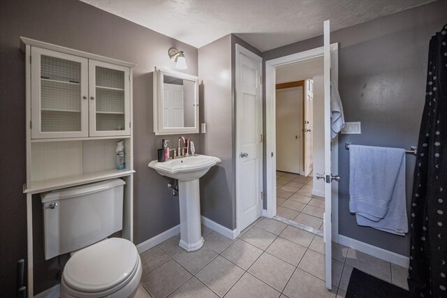 bathroom featuring tile patterned floors, baseboards, and toilet
