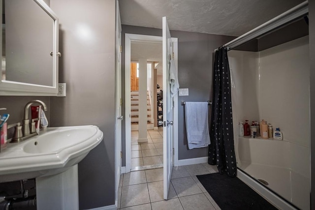 full bathroom with a stall shower, tile patterned flooring, baseboards, and a sink