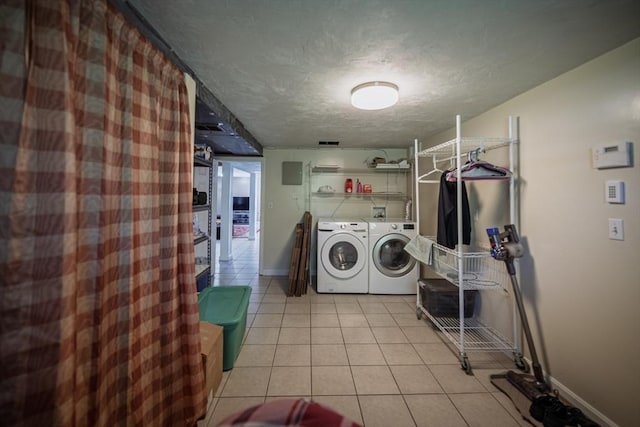 laundry area with washing machine and clothes dryer, light tile patterned flooring, a textured ceiling, and baseboards