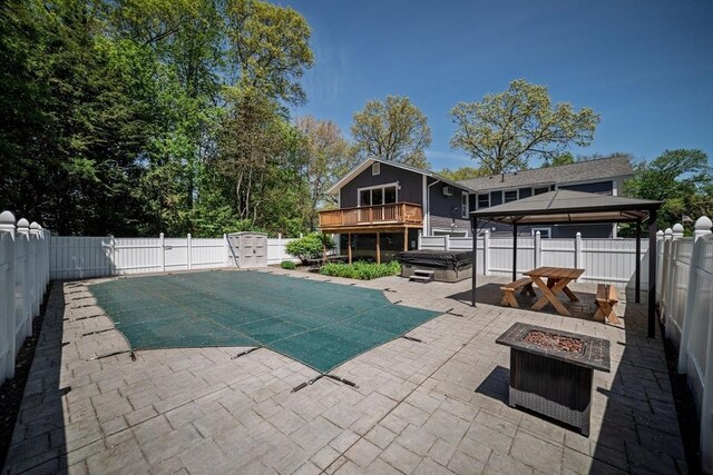 view of swimming pool featuring a hot tub, a fire pit, a patio, a fenced backyard, and a gazebo