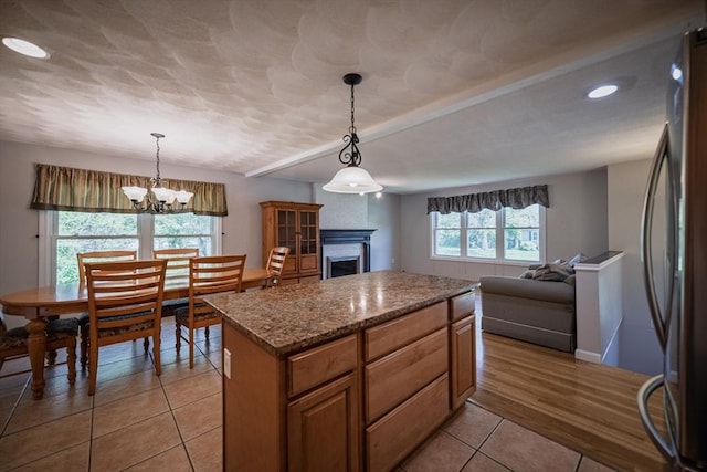 kitchen with light tile patterned floors, recessed lighting, a fireplace, a center island, and freestanding refrigerator