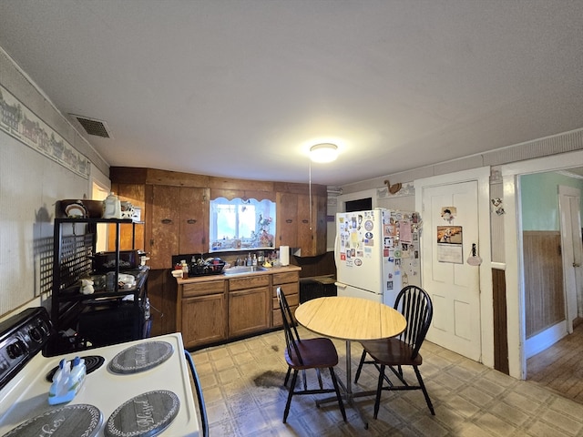 kitchen with white appliances, wooden walls, and sink