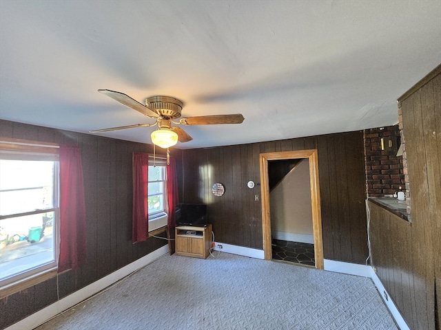 spare room featuring wooden walls, carpet, and ceiling fan