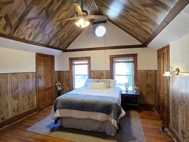 bedroom featuring ceiling fan, wood walls, dark hardwood / wood-style flooring, and lofted ceiling with beams