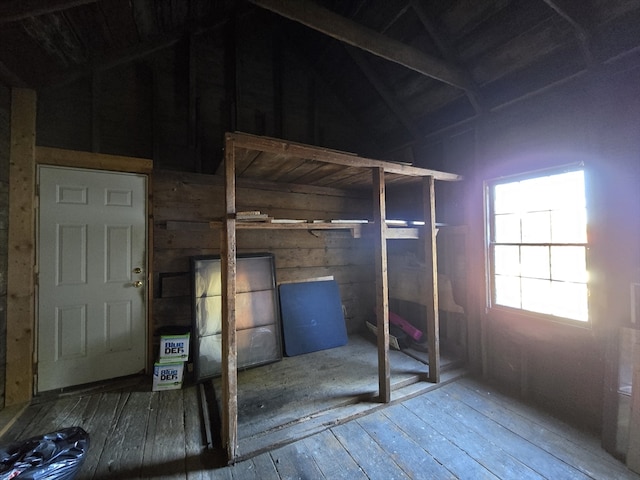 unfurnished bedroom featuring lofted ceiling, wooden walls, and hardwood / wood-style flooring