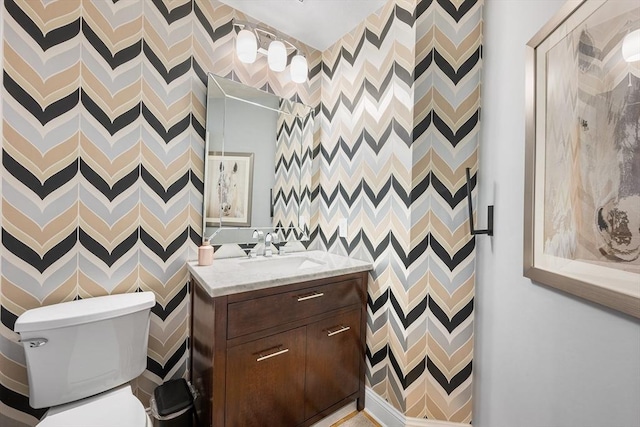 bathroom featuring vanity, toilet, and a decorative wall