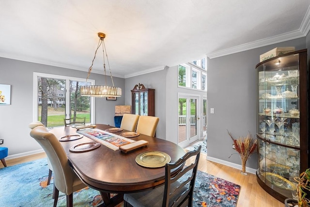 dining room with crown molding, baseboards, french doors, and light wood-type flooring