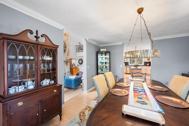 dining space with light wood-style floors and crown molding