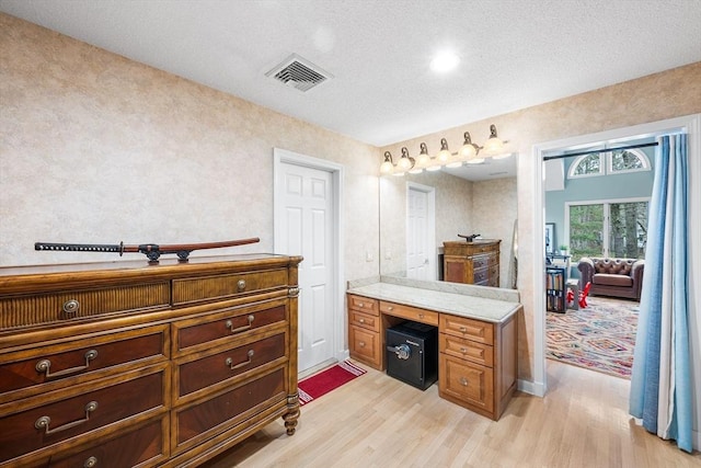 bathroom featuring a textured ceiling, vanity, wood finished floors, and visible vents