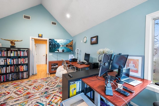 office with high vaulted ceiling, wood finished floors, and visible vents