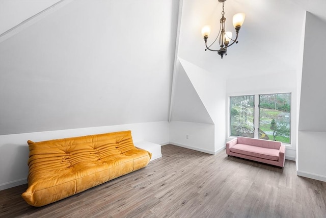 living area featuring baseboards, wood finished floors, a notable chandelier, and vaulted ceiling
