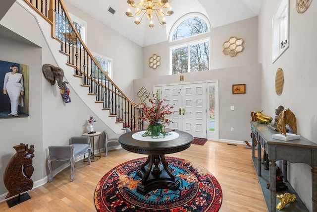 entryway featuring an inviting chandelier, high vaulted ceiling, stairs, and wood finished floors