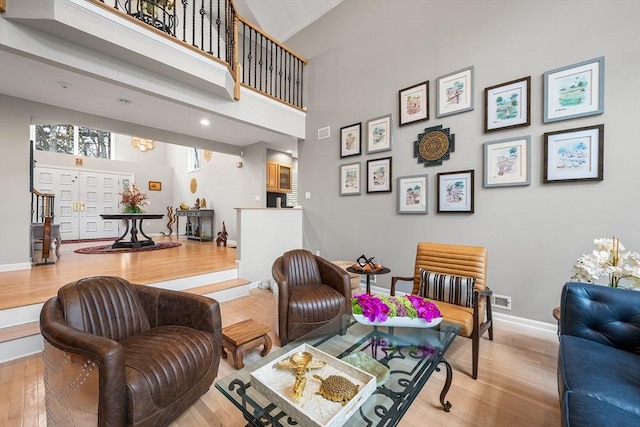 living area with baseboards, a high ceiling, wood finished floors, and visible vents