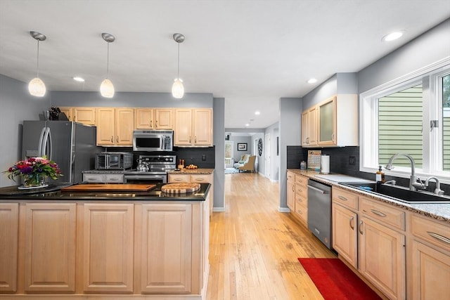 kitchen with tasteful backsplash, a sink, light brown cabinets, stainless steel appliances, and light wood-type flooring