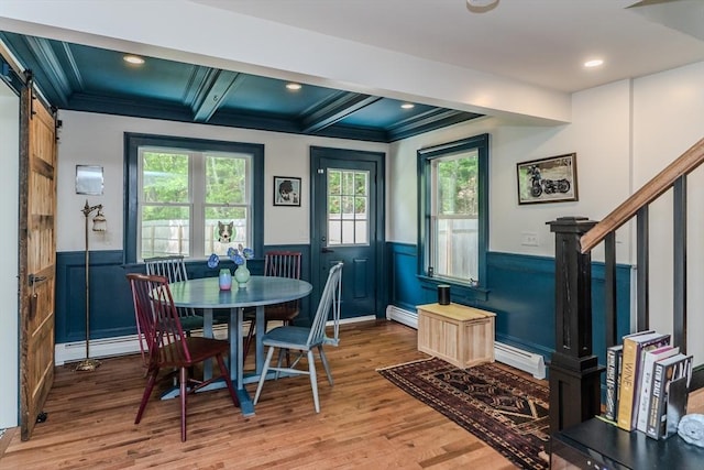 dining area featuring a wainscoted wall, a baseboard heating unit, light wood-type flooring, ornamental molding, and beamed ceiling
