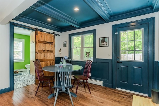 dining area with ornamental molding, a barn door, wood finished floors, healthy amount of natural light, and beam ceiling
