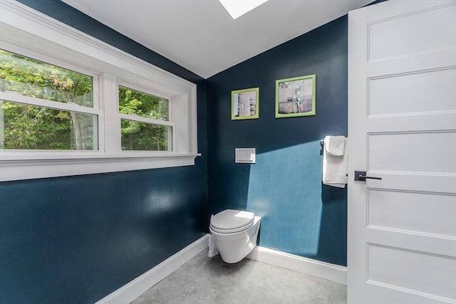bathroom featuring baseboards, lofted ceiling, and toilet