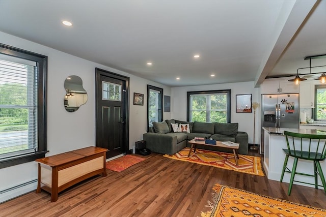 living area featuring a baseboard heating unit, wood finished floors, plenty of natural light, and recessed lighting