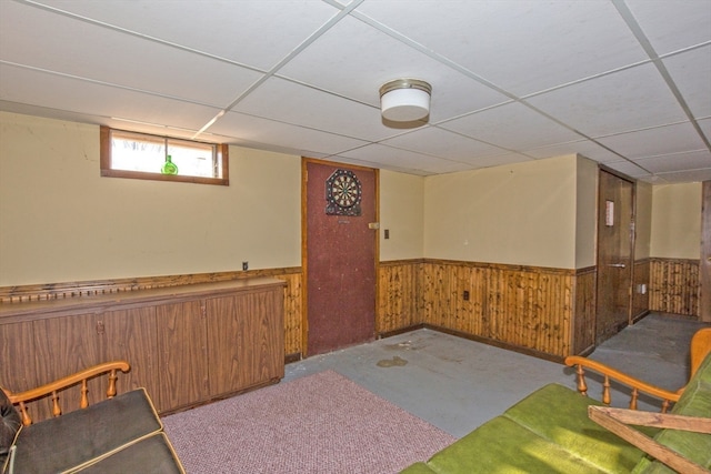 basement with a drop ceiling and wood walls