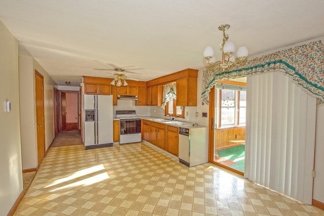 kitchen featuring ceiling fan with notable chandelier, decorative light fixtures, sink, and white appliances