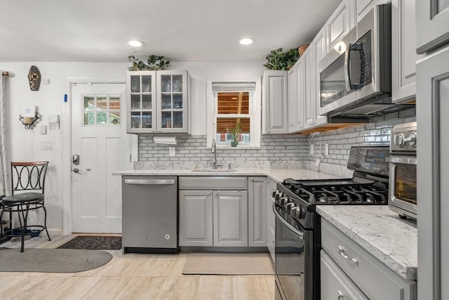 80 Messinger St, Boston, MA 02126 - kitchen featuring appliances with stainless steel finishes, a sink, backsplash, glass insert cabinets, and light stone counters