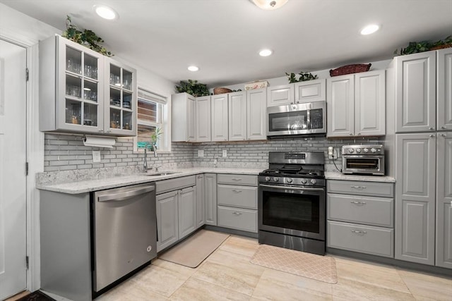 80 Messinger St, Boston, MA 02126 - kitchen with appliances with stainless steel finishes, gray cabinets, a sink, tasteful backsplash, and glass insert cabinets