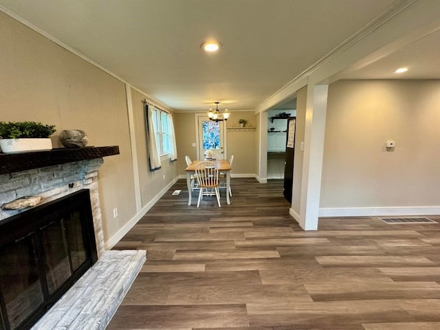 dining space featuring dark hardwood / wood-style flooring, a chandelier, a fireplace, and ornamental molding