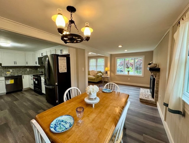 dining area with a notable chandelier, dark wood-type flooring, ornamental molding, and a fireplace