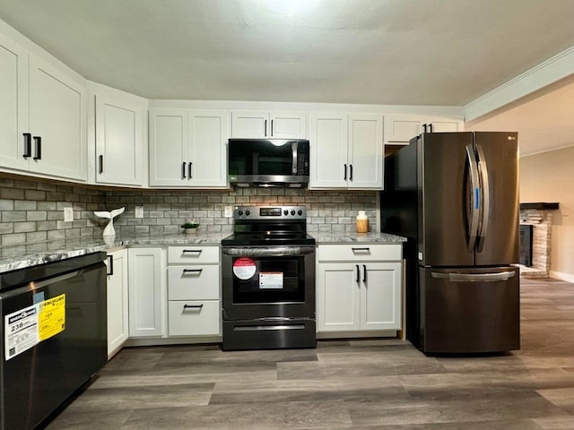 kitchen featuring appliances with stainless steel finishes, white cabinetry, hardwood / wood-style flooring, and light stone countertops