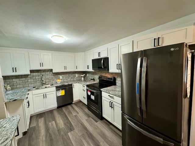 kitchen with dark hardwood / wood-style flooring, black appliances, white cabinets, light stone counters, and sink