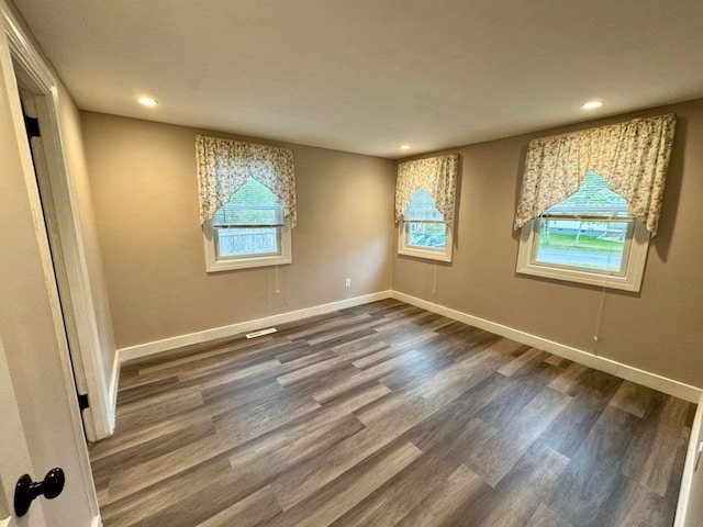 unfurnished room featuring plenty of natural light and dark hardwood / wood-style floors