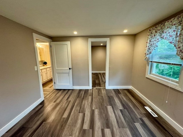 unfurnished bedroom with dark hardwood / wood-style flooring, ensuite bath, and a spacious closet