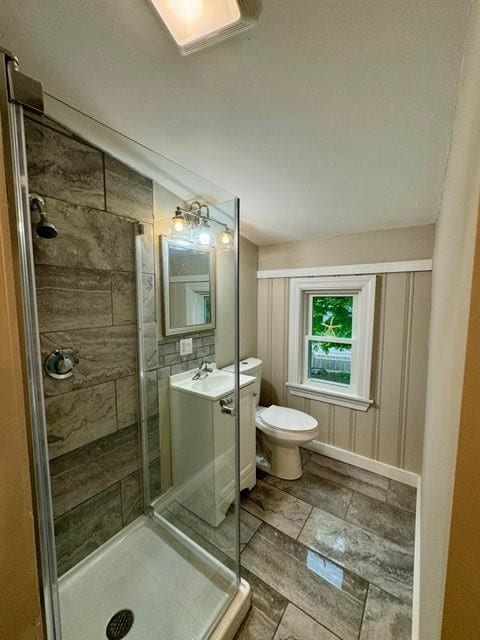 bathroom with tile flooring, an enclosed shower, toilet, and vanity