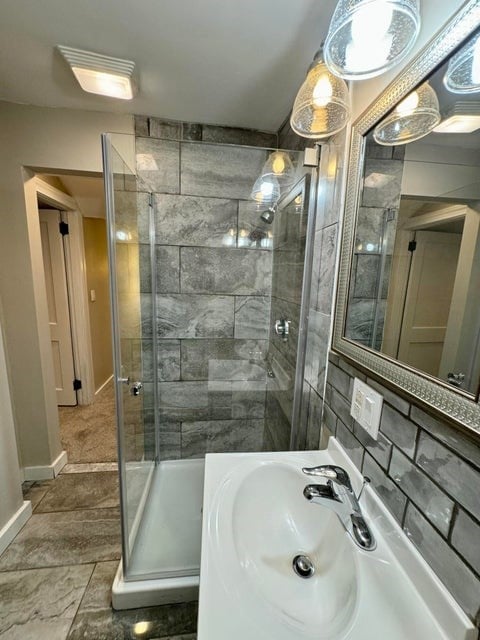 bathroom featuring tile floors, a shower with door, sink, and tasteful backsplash