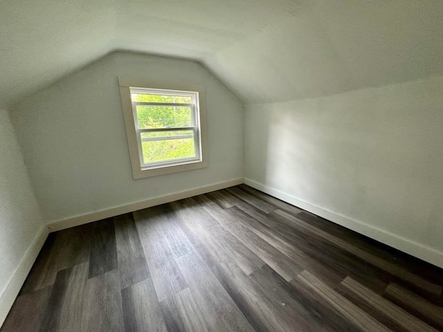 additional living space with dark wood-type flooring and vaulted ceiling