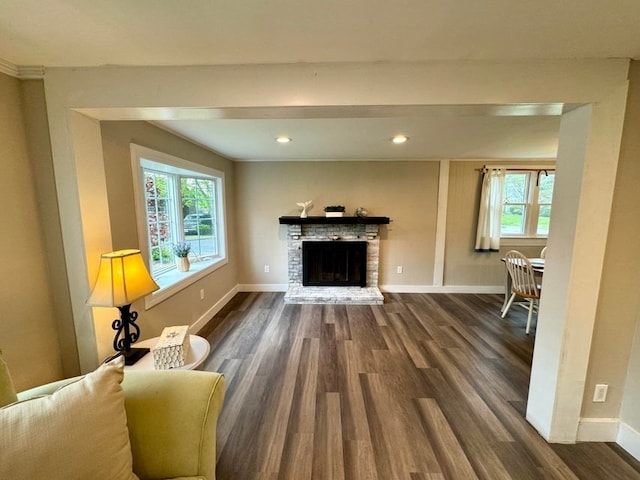 living room featuring dark wood-type flooring and a brick fireplace