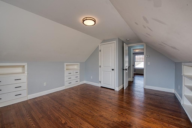 bonus room with built in features, lofted ceiling, dark wood finished floors, and baseboards